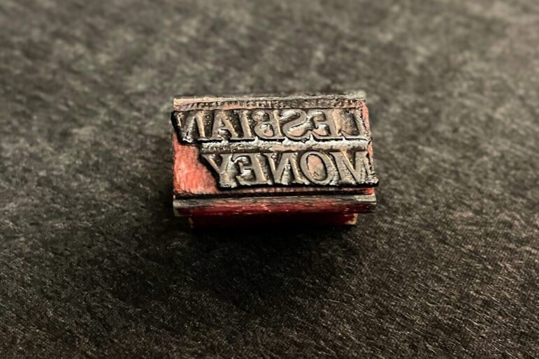 The rubber stamp used to print "lesbian money" on dollar bills