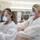 Ensign Kaitlyn Leibing, right, a staff nurse assigned to one of Naval Medical Center San Diego’s internal medicine wards, helps Hospitalman Angela Mello don personal protective equipment before entering a COVID-19-positive, non-critical patient’s room on Aug. 4, 2020.