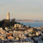 Coit Tower and the San Francisco Bay are seen behind apartment buildings in San Francisco's North Beach neighborhood.