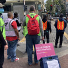 Outreach workers stand at a Tenderloin intersection wearing reflective vests and pulling a rolling cart with a sign reading “free COVID-19 vaccinations here.” This team administered 23 single-dose vaccines during an afternoon shift on Jul. 15, 2021.