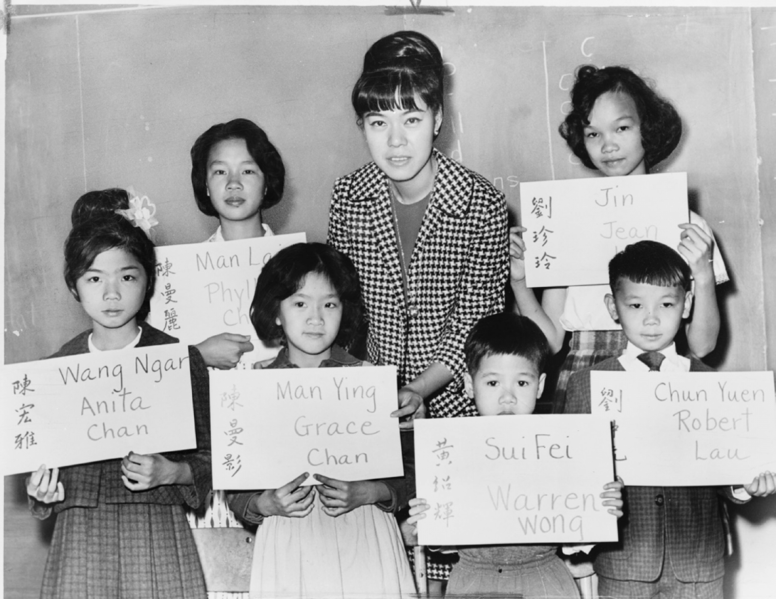 Six Chinese children who had recently arrived in New York City in 1964 with their teacher. The placards show their Chinese names, in ideographs and in transliteration, and the names to be entered in official school records. Library of Congress
